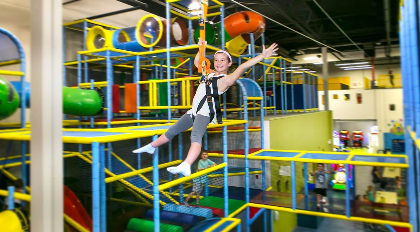 Child zip-lining in indoor playground with colorful climbing structures and tunnels, Allstars Indoor Playland Edmonton